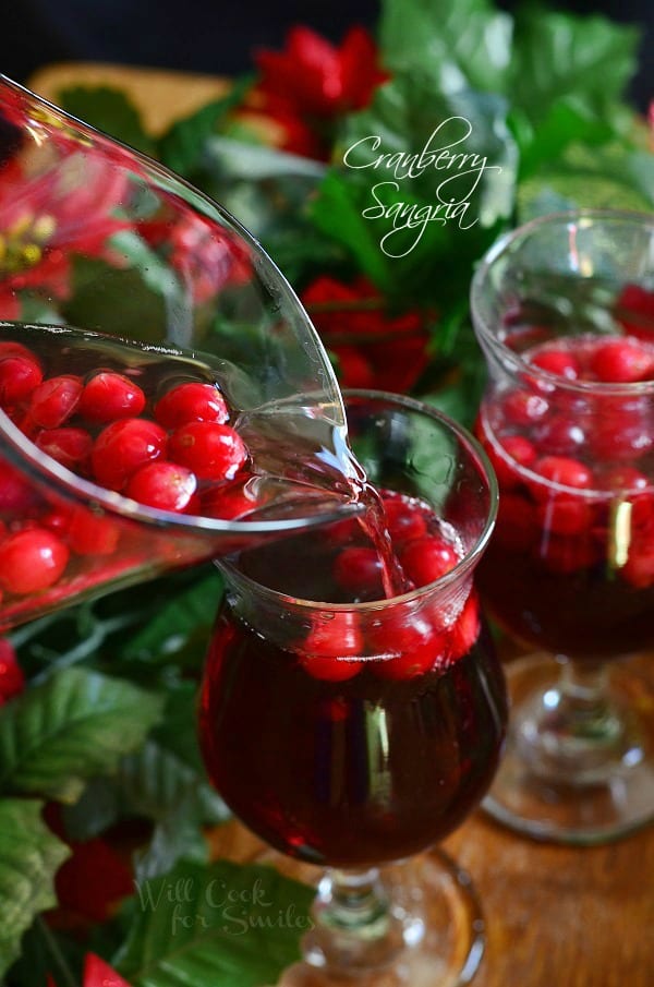 Cranberry Sangria being poured out of a pitcher into a glass 