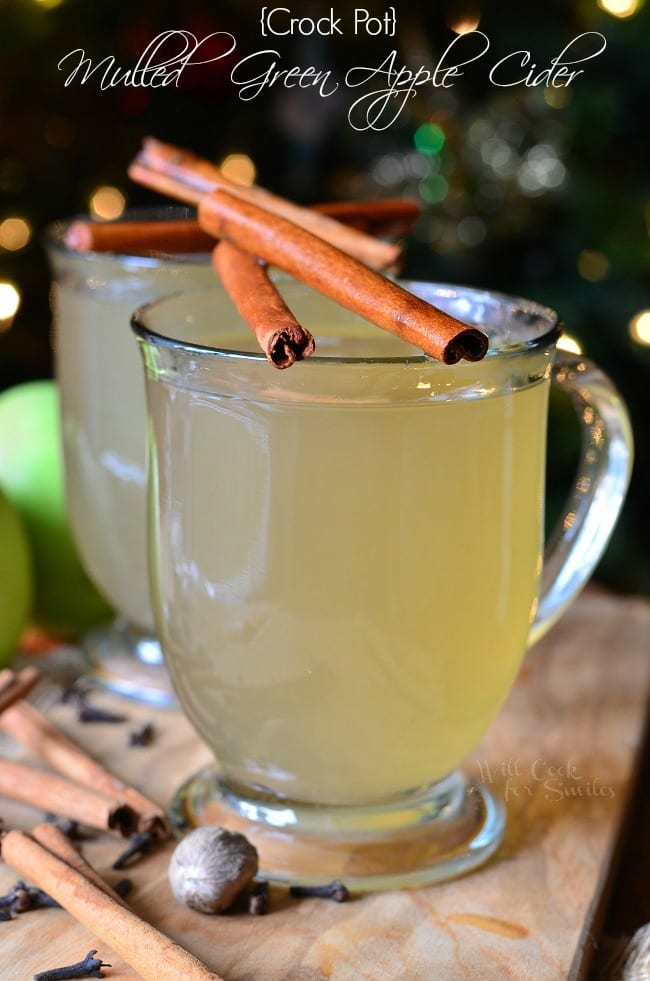 Green Apple Cider in a clear glass with cinnamon sticks over the top 