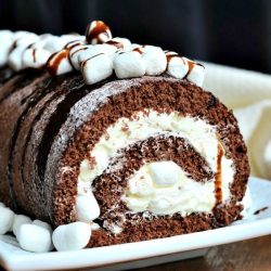 close up view of white rectangular plate with a whole hot chocolate cake roll on a wooden table with a white cloth in background