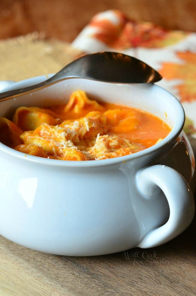 Roasted Bell Pepper Tortellini Soup in a white soup bowl with a spoon across the back 