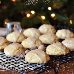 spiced eggnog cookies with eggnog glaze on a wire rack with a brown placemat cloth below on a wooden table