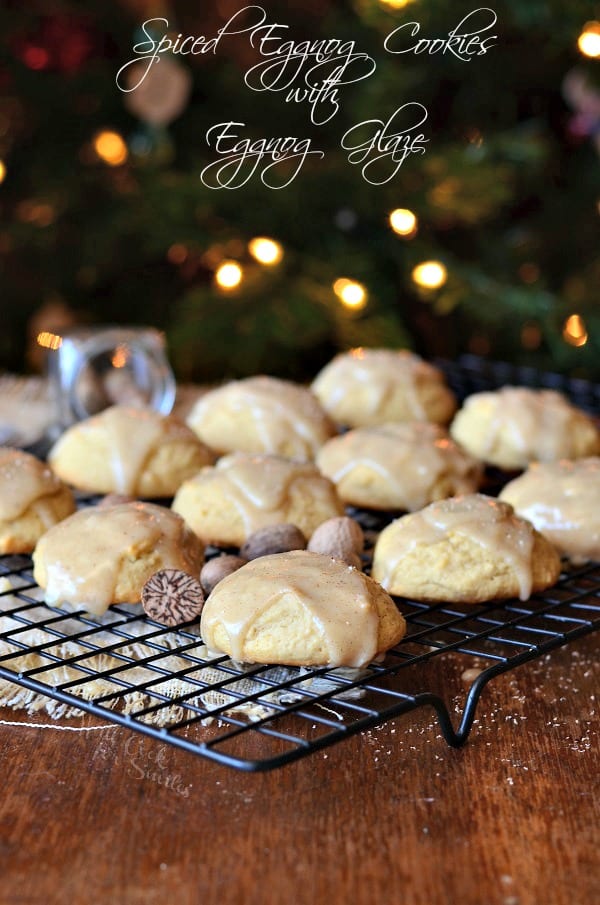 spiced eggnog cookies with eggnog glaze on a wire rack with a brown placemat cloth below on a wooden table