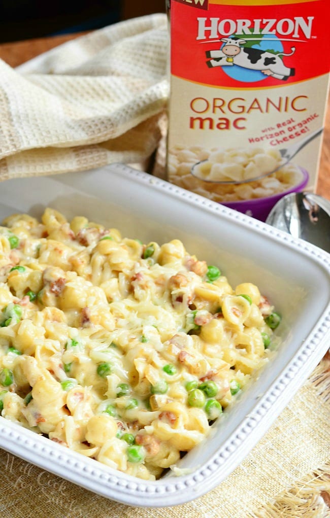 Creamy White Macaroni & Cheese with Peas Onions & Bacon in a white baking dish 