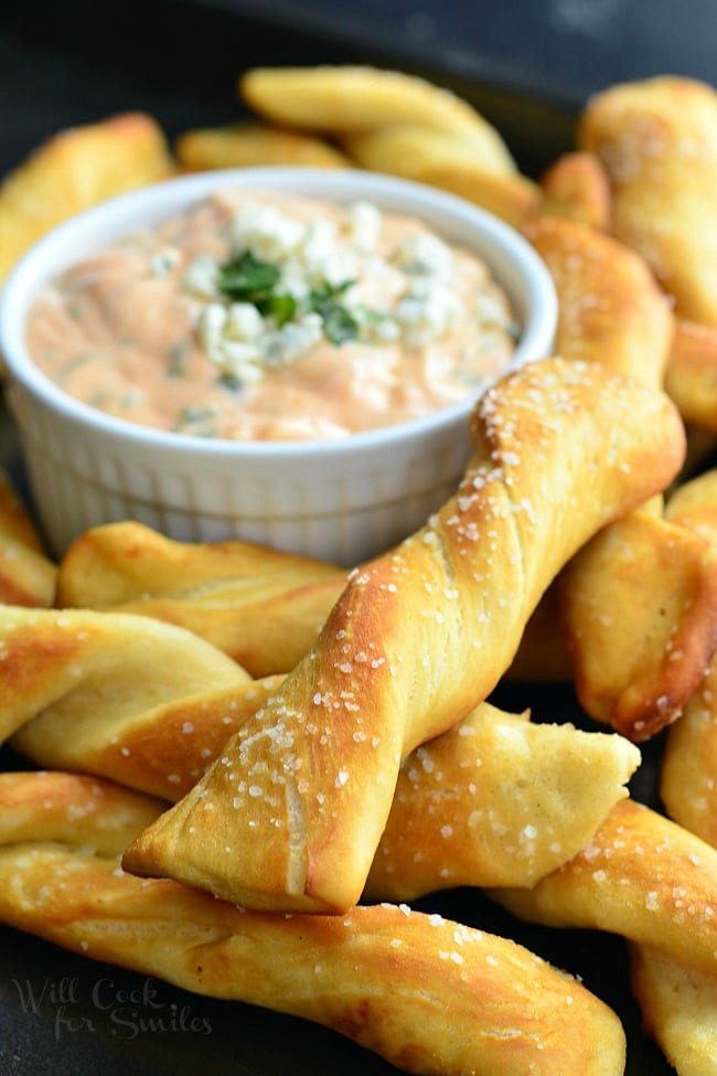 Homemade Soft Pretzel Twists on a cutting board with Creamy Buffalo Sauce in a bowl 