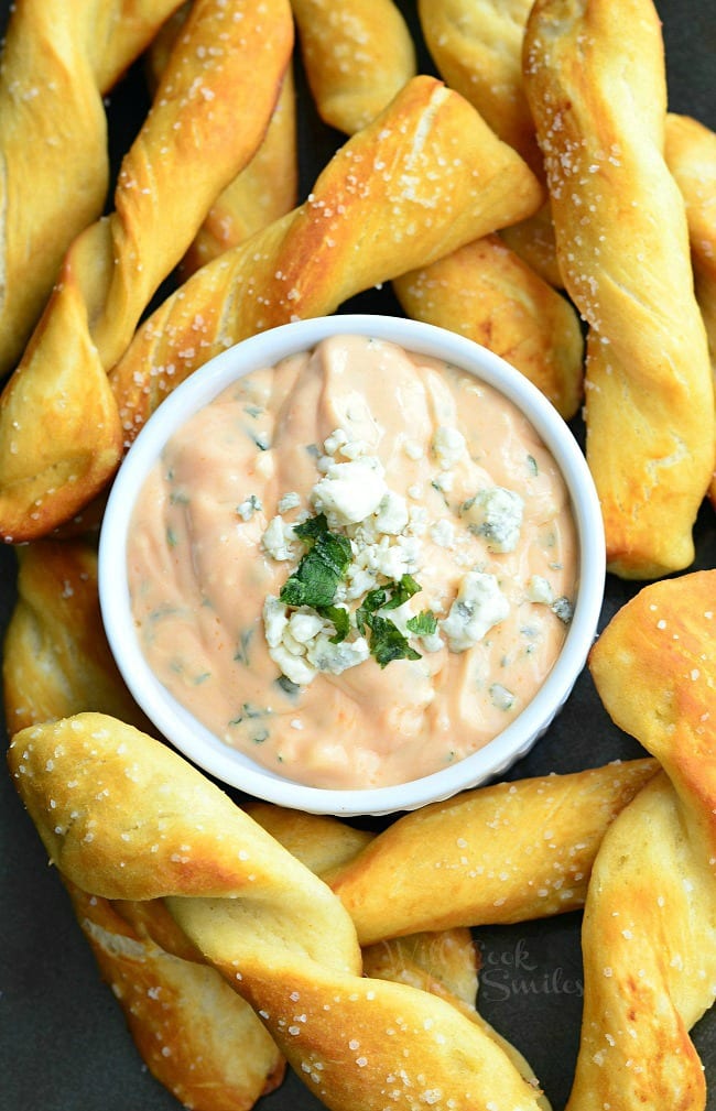 Viewed from above of white crock filled with creamy buffalo dipping sauce surounded by homemade soft pretzel twists