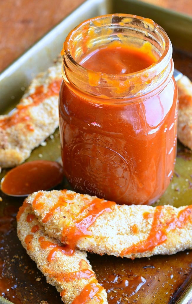 Whiskey BBQ Sauce in a mason jar with Chicken Strips on a baking sheet 