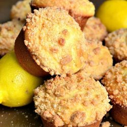 picture of lemon streusel muffins piled together with lemons at the bottom of the pileon a wooden table