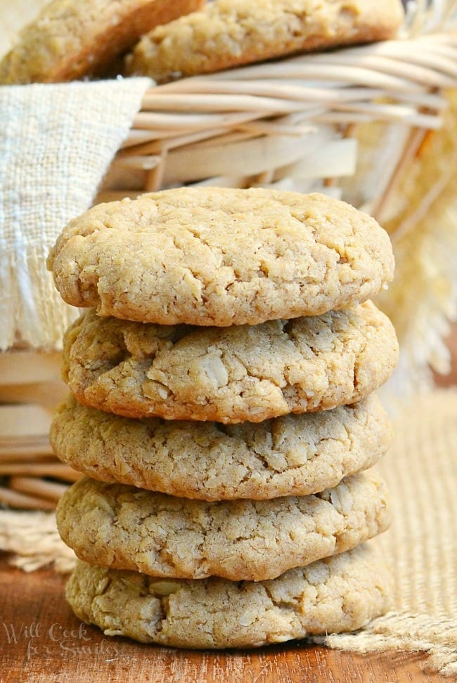 Soft Almond Butter Oatmeal Cookies stacked up on a table with a basket in the background with cookies in it  