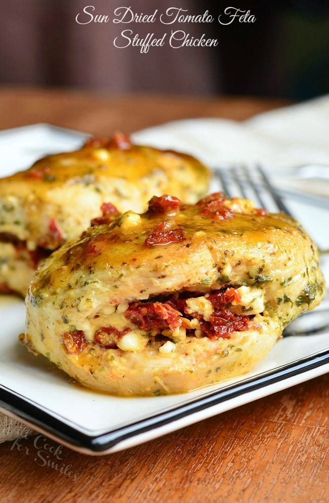 Two pieces of Sun Dried Tomato Feta Stuffed Chicken on a white dish with a fork.