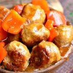 wooden bowl over flowing with sweet and sour turkey meatballs topped with peppers on a wooden table