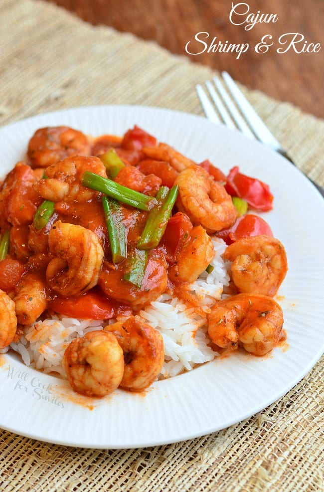 Cajun Shrimp over Rice on a plate with green onions on top and a fork to the right 