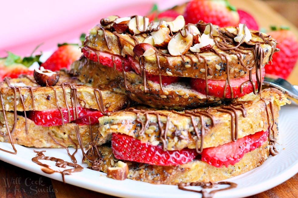 horizonal photo of Fruit Filled Hazelnut French Toast with strawberries stacked up on a white plate 