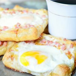 shignled pile of Ham egg cheese breakfast pastry and a cup of coffee on a sheet try and table