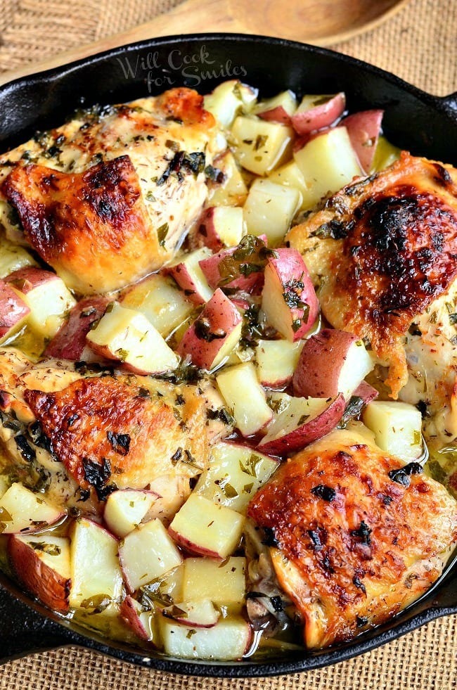four cooked chicken thighs and potatoes in the skillet