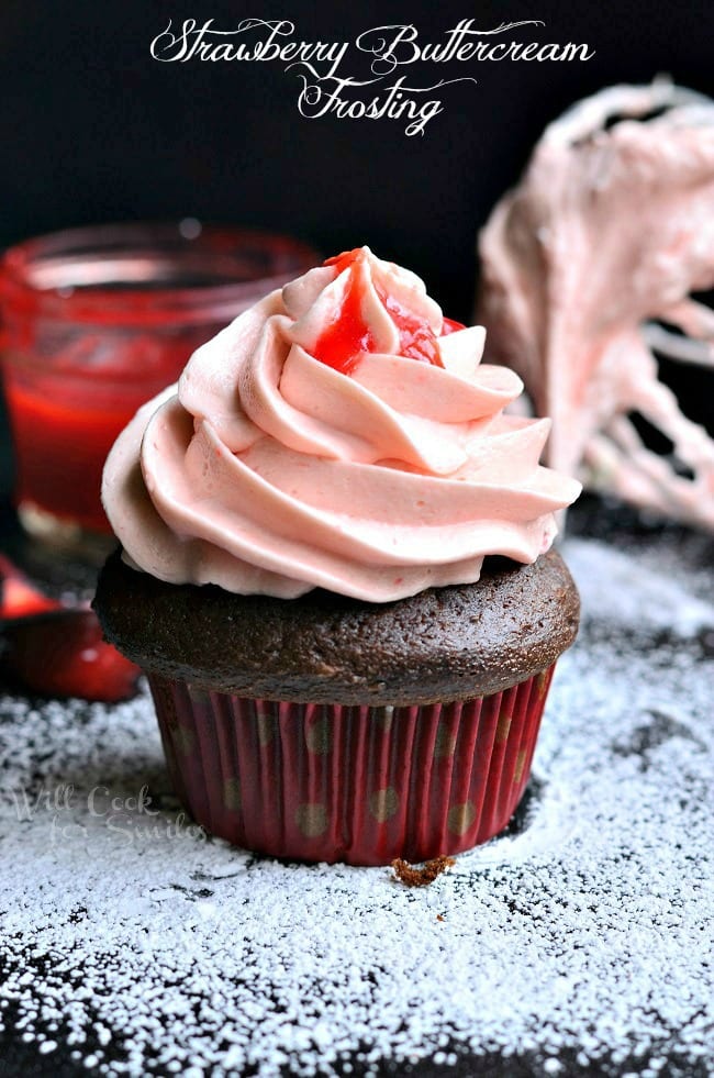 Strawberry Buttercream Frosting on a chocolate cupcake with powdered sugar on the table 