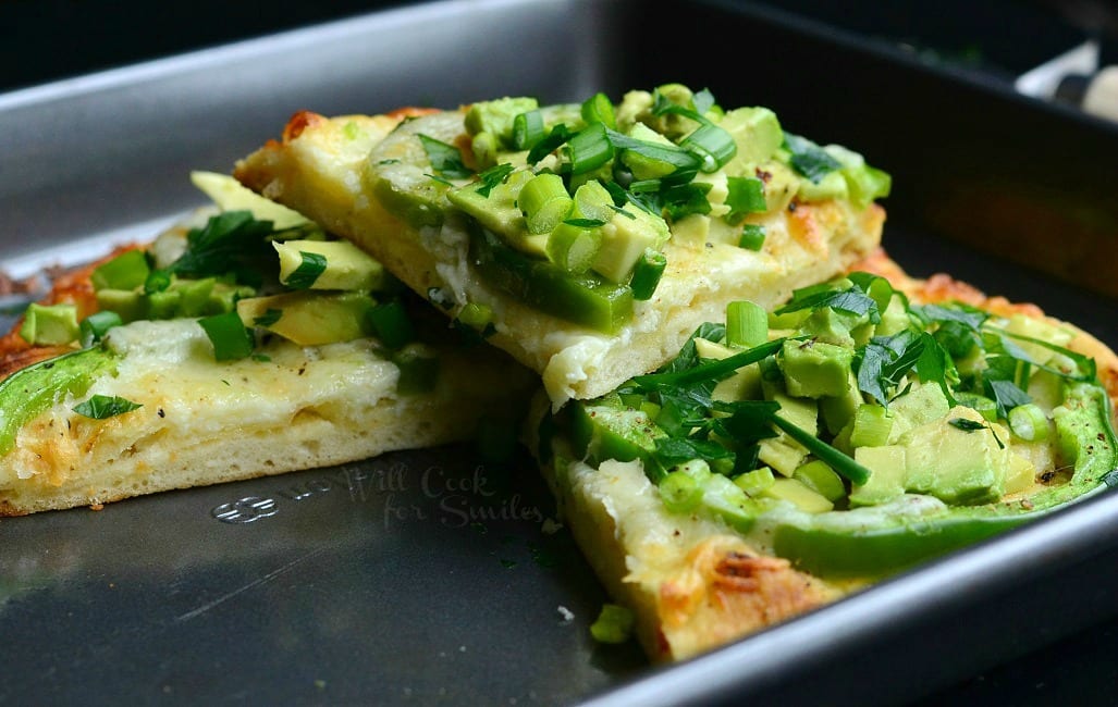 Green Naan Pizza with avocado, green peppers and green onions on top in a baking pan 