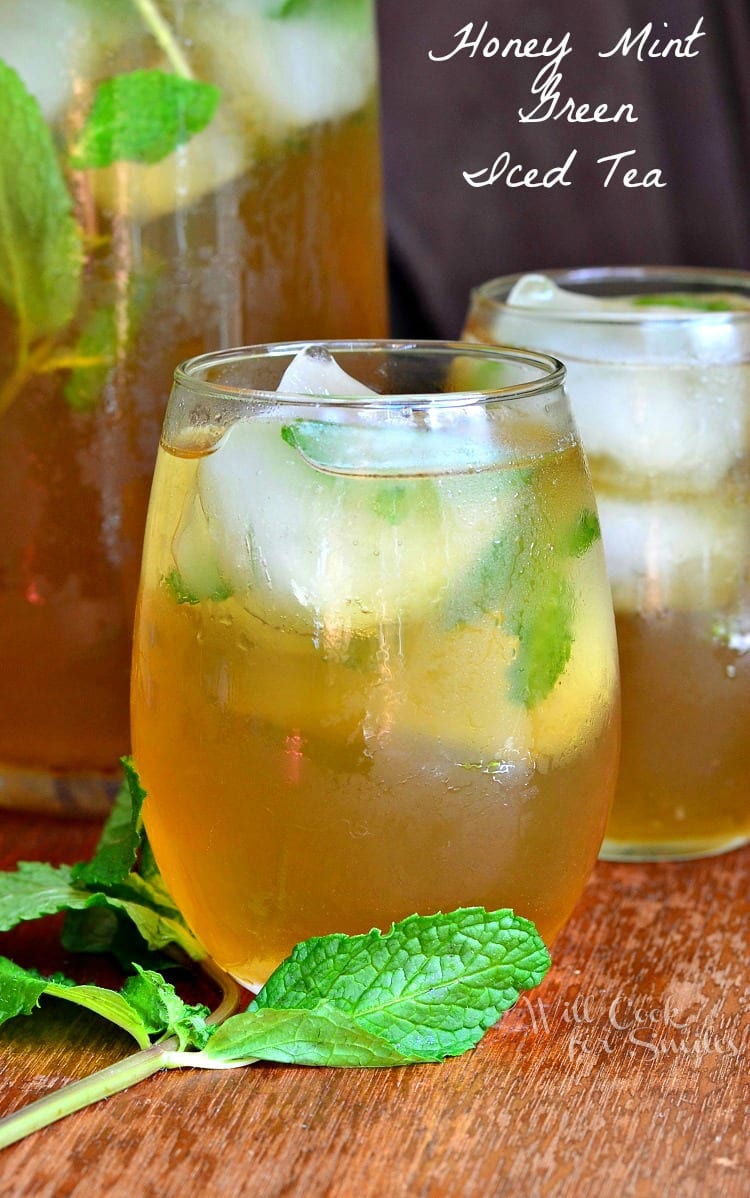 Honey Mint Green Iced Tea in a stemless wine glass with mint around it on a cutting board 