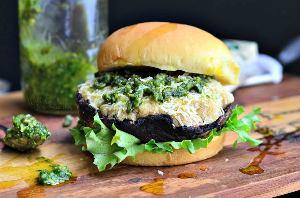 Italian Stuffed Portobello Burger on a bun with lettuce and pesto on top on wood cutting board 