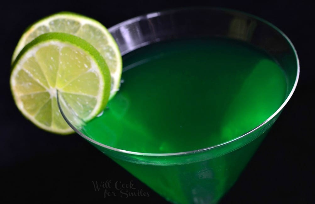 close up of green martini in a glass with lime on the rim 