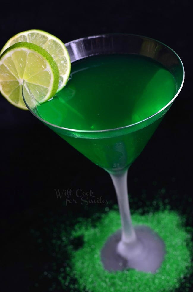 Lime Martini in a glass with lime on the edge and green sprinkles on the table around the glass 