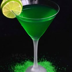 view from above of a martini glass filled with lime martini and garnished with lime garnishes