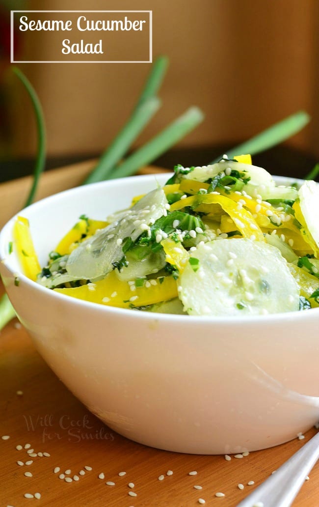 Sesame Cucumber Salad with yellow bell peppers on a wood tray with sesame seeds 