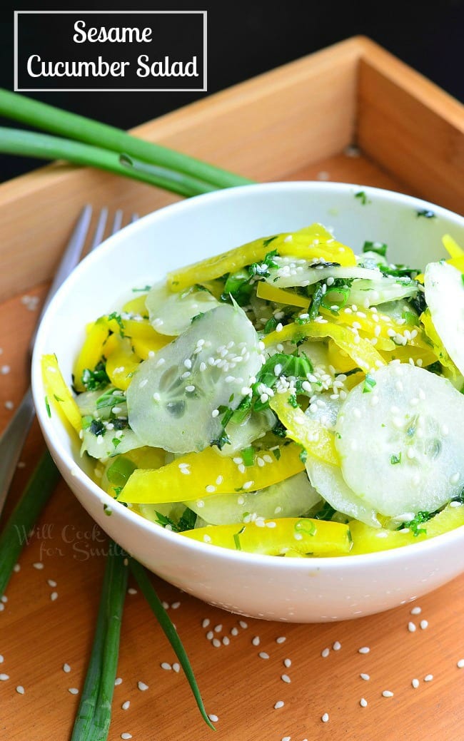 Sesame Cucumber Salad with yellow bell peppers on a wood tray with sesame seeds and a fork to the left 