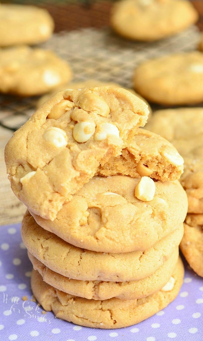 Peanut Butter White Chocolate Cookies stacked up on a napkin  with the top cookie cut in half 