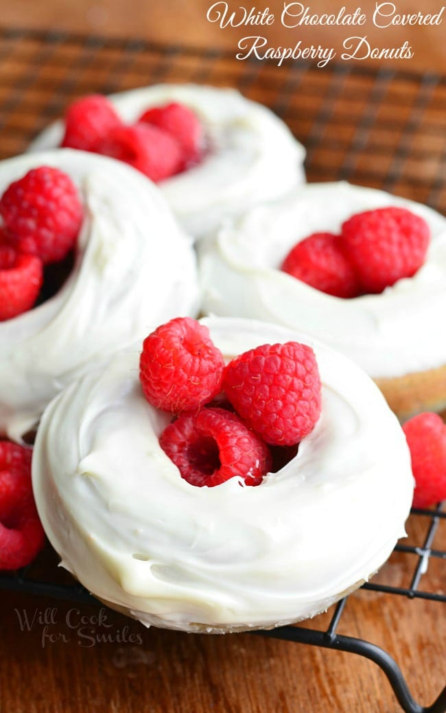 White Chocolate Covered Baked Raspberry Donuts with raspberries in the center on a cooling rack 