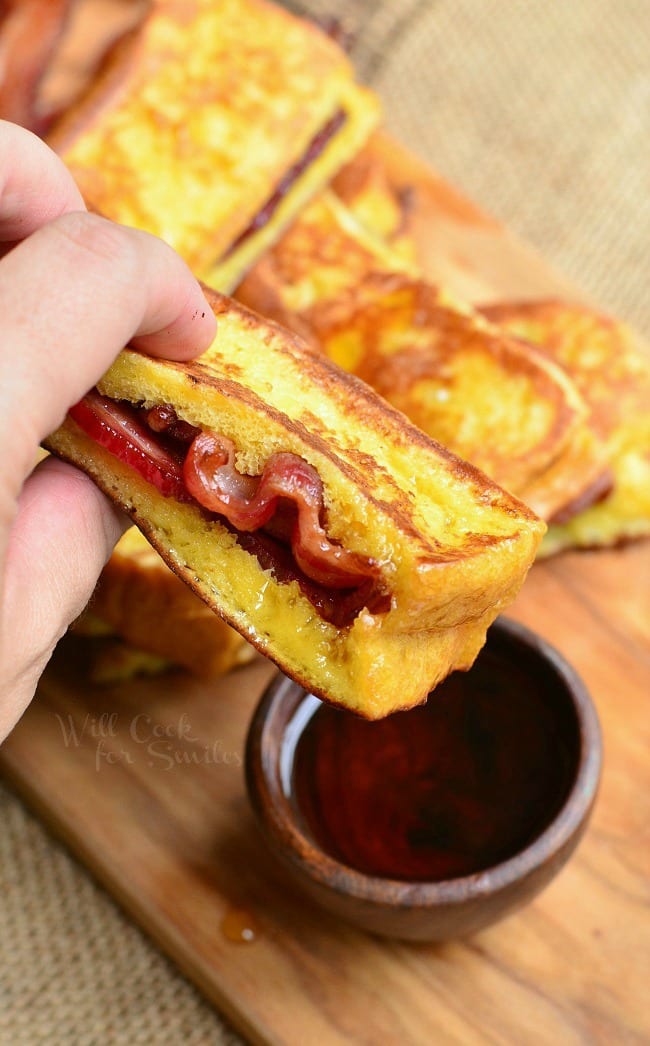 holding the french toast stick closer with bacon in the center