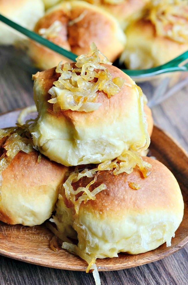 Caramelized Onion Dinner Rolls with onions on top on a wood plate 