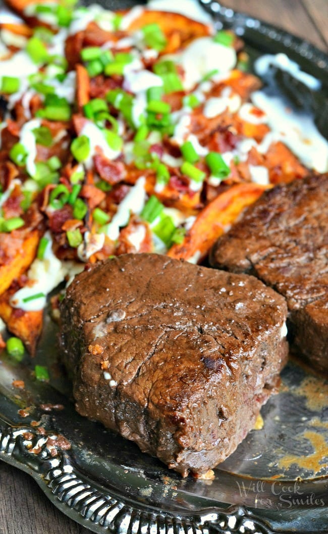 Ribeye Filet and Loaded Sweet Potato Wedges on  a plate a fork taking a piece of the streak 