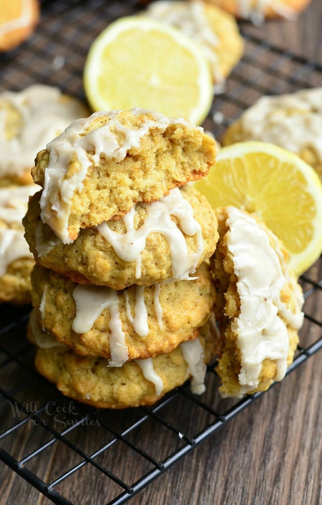 Glazed Lemon Vanilla Oatmeal Cookies stacked up on a cooling rack with a lemon cut in half 