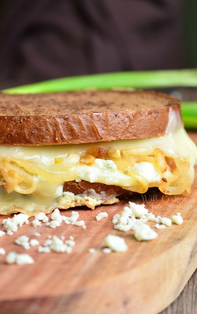 Gruyere and Caramelized Onion Grilled Cheese made with Gruyère cheese, blue cheese crumbles and caramelized onions. on a cutting board 