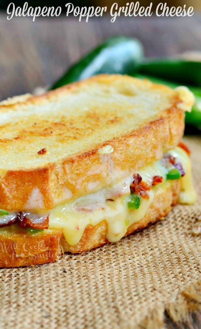 Close up view of a whole jalapeno popper grilled cheese on a burlap cloth with peppers in the background