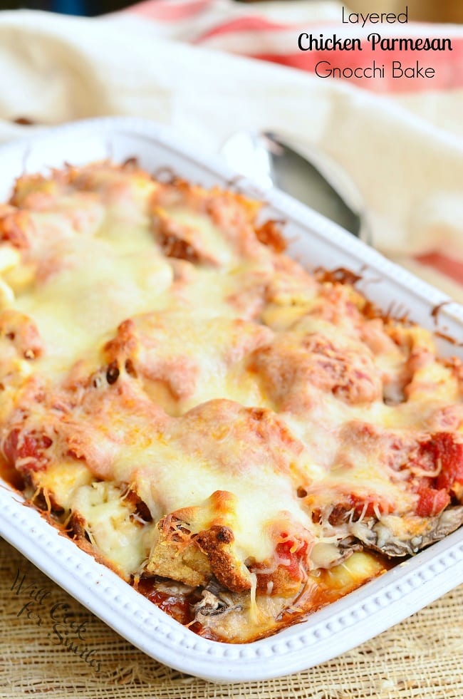 Layered Chicken Parmesan Gnocchi Bake served in a white casserole dish. The top is smothered in melted cheese.