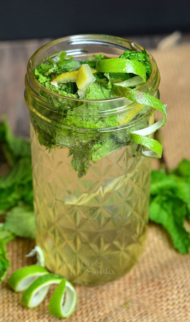 Lemon Lime Mojitos in a mason jar with limes and mint inside and around the base of the jars on the table top 