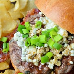 view from above of blue cheese bacon burger and chips on a wooden cutting board