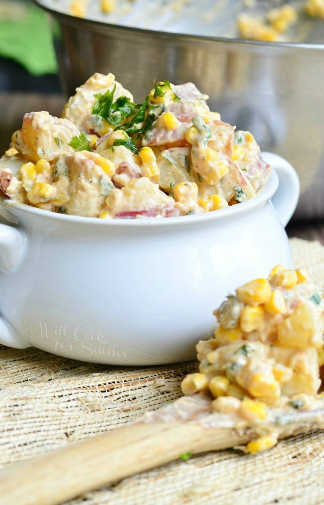 Chipotle Ranch Potato Salad with potatoes, corn, and parsley on top  in a white bowl 