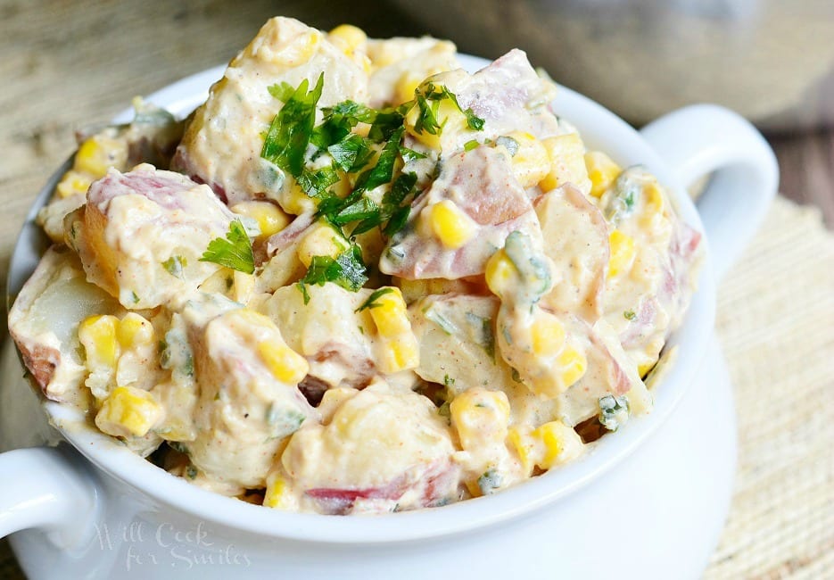 Chipotle Ranch Potato Salad with potatoes, corn, and parsley on top  in a white bowl 