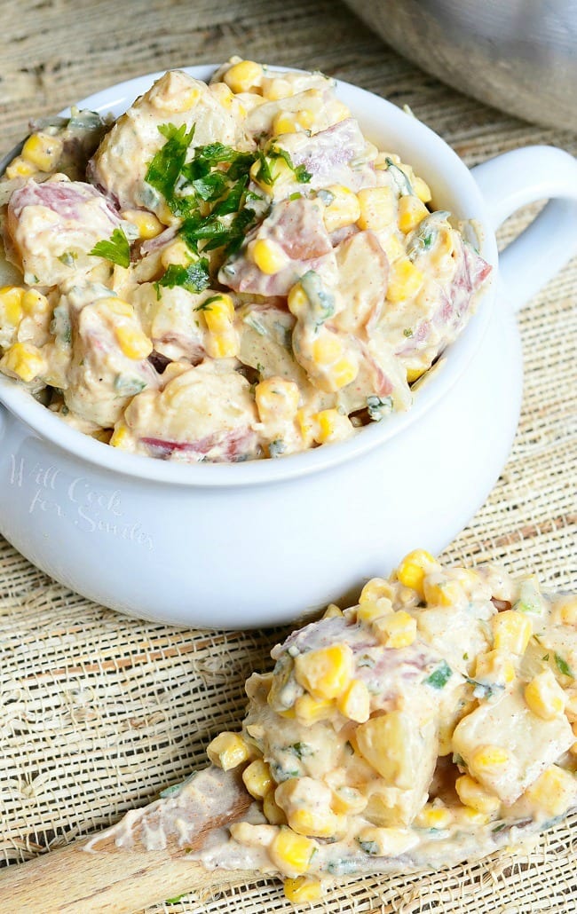 Chipotle Ranch Potato Salad with potatoes, corn, and parsley on top  in a white bowl 