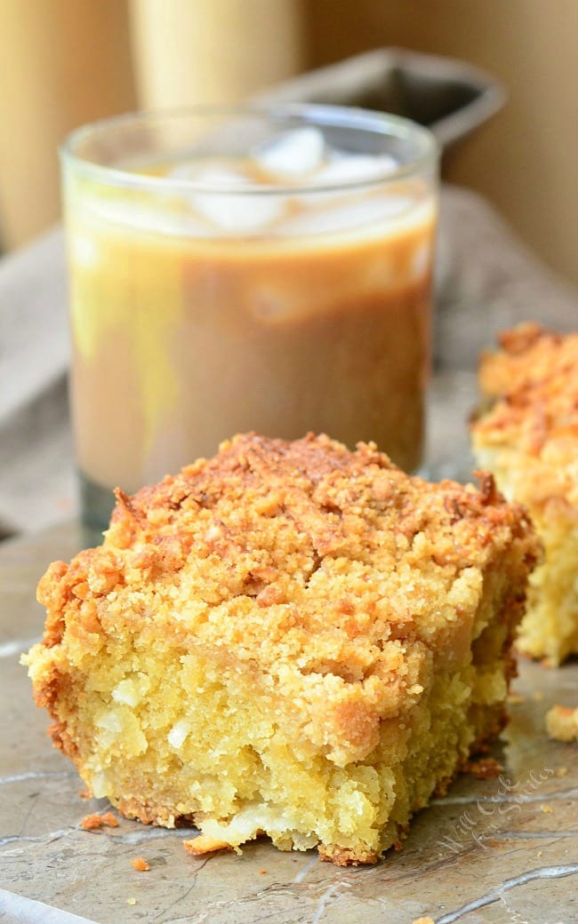 Coconut Coffee Cake slice on a table with ice coffee in a glass 