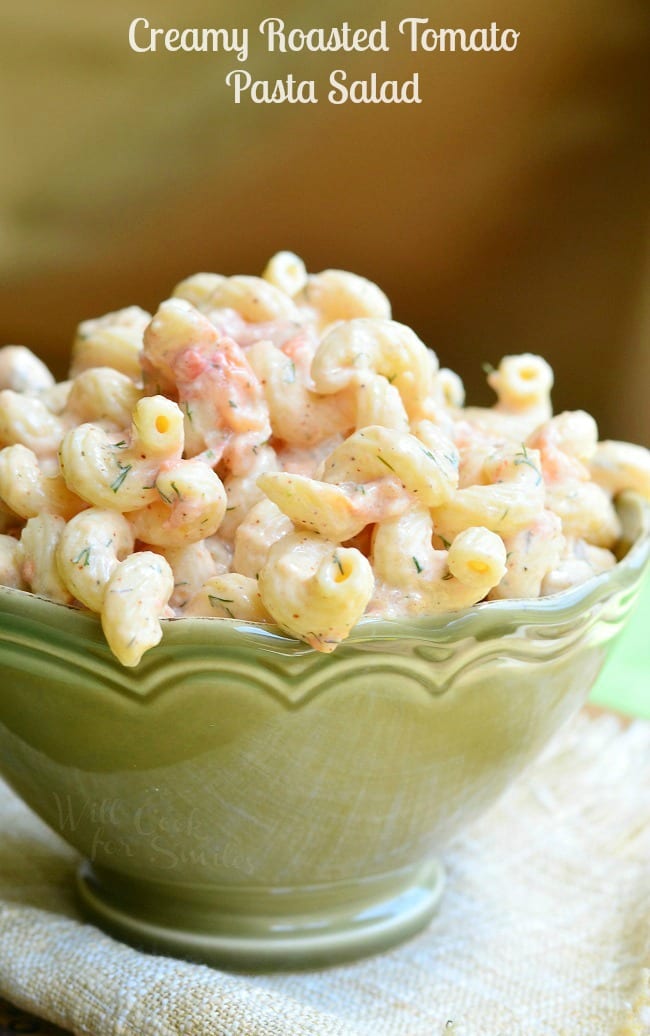 Creamy Roasted Tomato Pasta Salad is served in a green serving dish. There are lots of spiral noodles in a creamy coating.