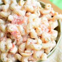 view from above of small green bowl filled with creamy roasted tomato pasta salad on a tan cloth