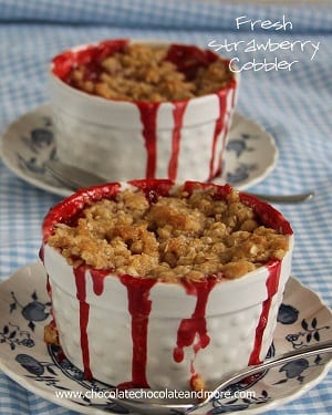 Strawberry cobbler in a white bowl on a plate with a spoon 