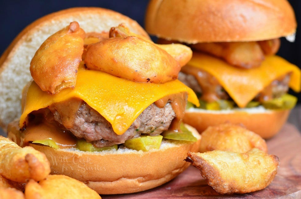 Onion Ring BBQ Cheeseburger, two cheeseburgers on a bun with pickles under it and onion rings on top and around it 