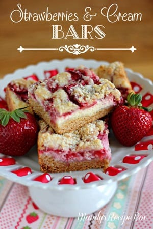 strawberry bars on a cake platter with strawberries around it 