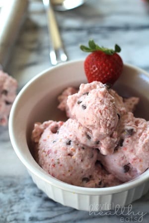 strawberry ice cream in a white bowl with a strawberry as garnish 