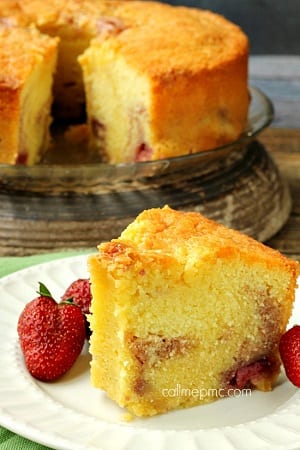 slice of strawberry pound cake on a white plate with whole strawberries as a garnish 