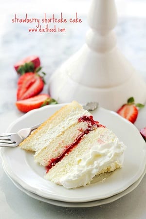 slice of strawberry shortcake on a white plate with a fork behind it 